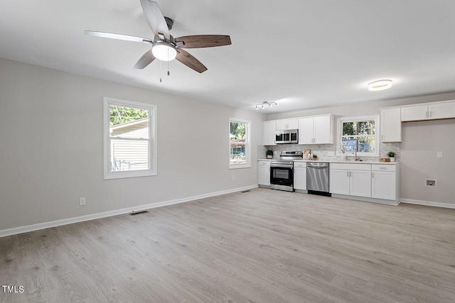 kitchen featuring sink, a wealth of natural light, appliances with stainless steel finishes, light hardwood / wood-style floors, and white cabinetry