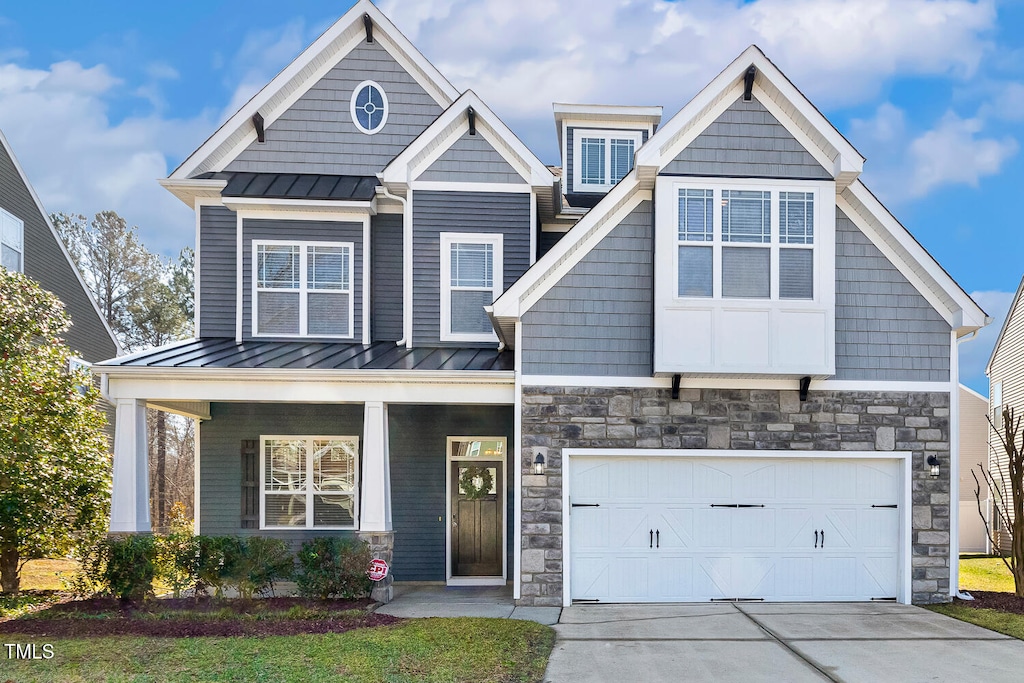 craftsman-style home with stone siding, a standing seam roof, metal roof, and concrete driveway