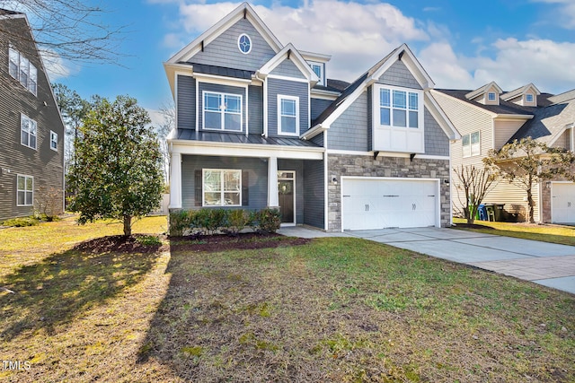 view of front of property with concrete driveway, an attached garage, a standing seam roof, stone siding, and a front lawn