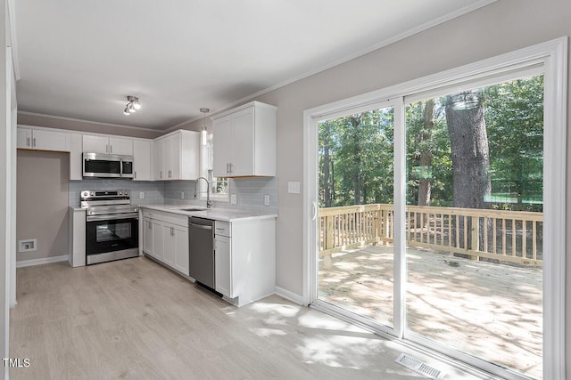 kitchen featuring white cabinetry, sink, decorative backsplash, appliances with stainless steel finishes, and light wood-type flooring