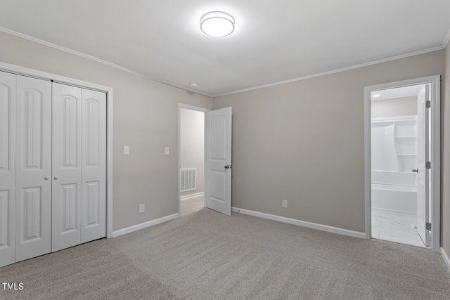 unfurnished bedroom with ensuite bath, crown molding, light carpet, and a closet