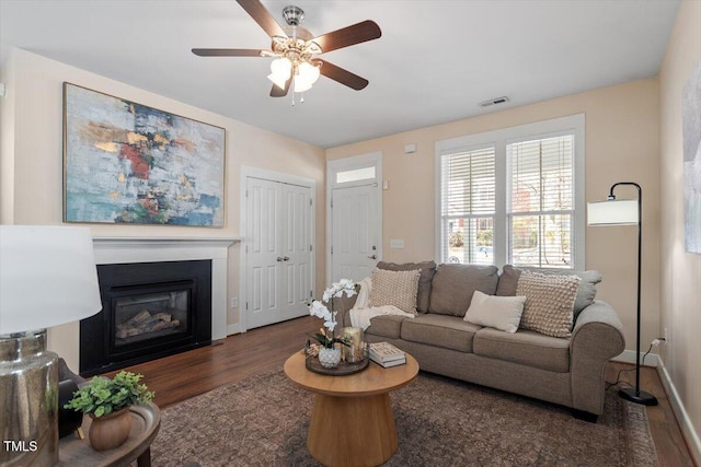 living room featuring ceiling fan and dark wood-type flooring