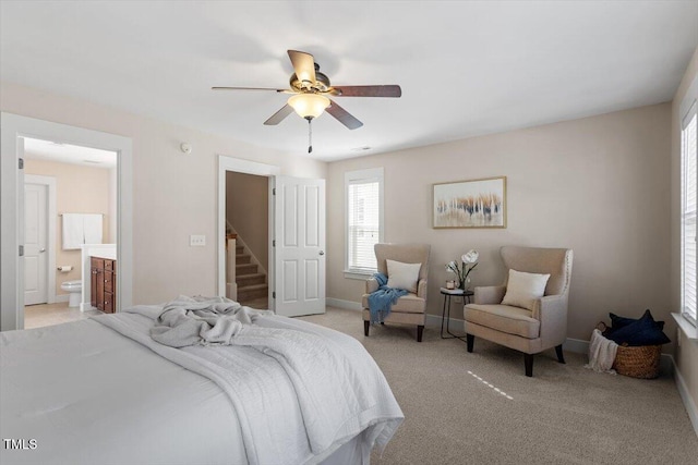 bedroom featuring ceiling fan, ensuite bath, and light colored carpet