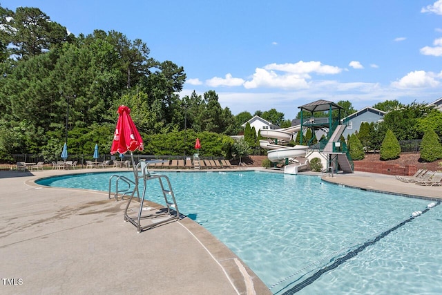 view of swimming pool featuring a patio, a playground, and a water slide