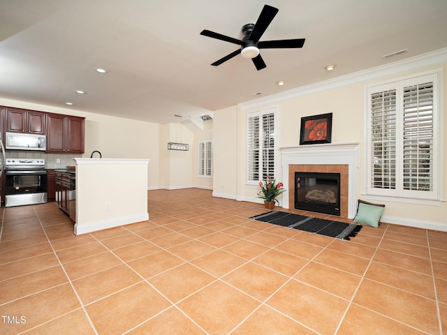 living room featuring a tiled fireplace, light tile patterned floors, ornamental molding, and ceiling fan