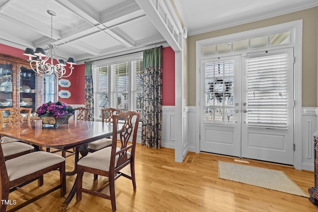 dining area with coffered ceiling, beamed ceiling, a notable chandelier, light hardwood / wood-style floors, and ornamental molding