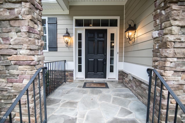 view of exterior entry with stone siding and a porch