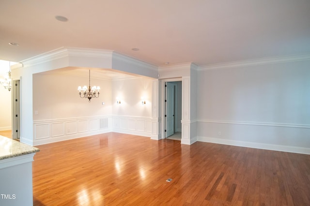 spare room with a chandelier, ornamental molding, and wood finished floors