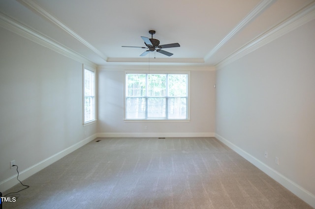 unfurnished room featuring a ceiling fan, baseboards, a tray ceiling, light carpet, and crown molding