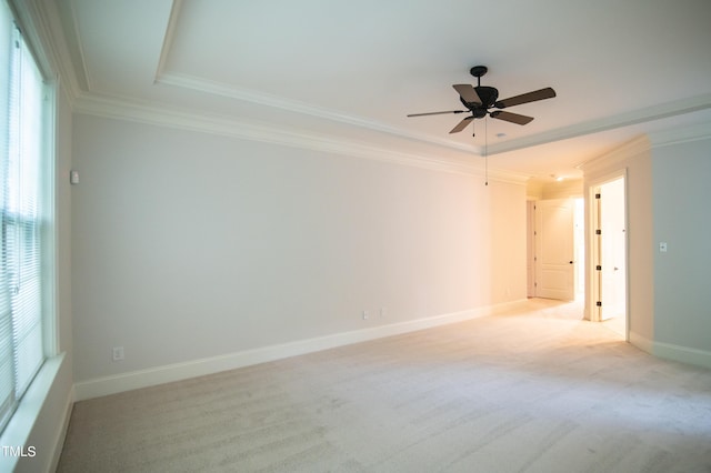 spare room with a ceiling fan, baseboards, ornamental molding, a raised ceiling, and light colored carpet