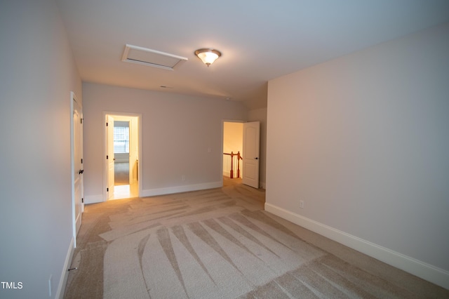 unfurnished room featuring attic access, light colored carpet, and baseboards