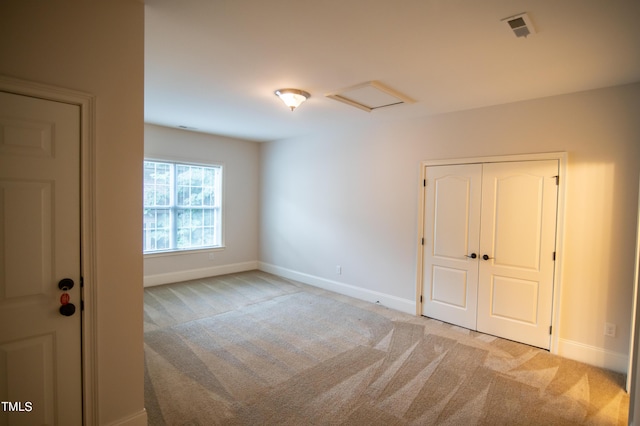 unfurnished room featuring attic access, baseboards, visible vents, and light carpet