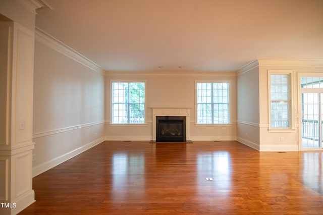 unfurnished living room with a glass covered fireplace, baseboards, wood finished floors, and crown molding