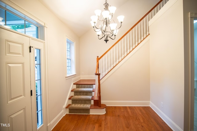 entrance foyer featuring stairs, wood finished floors, baseboards, and a chandelier