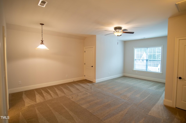 empty room with carpet flooring, baseboards, visible vents, and ceiling fan