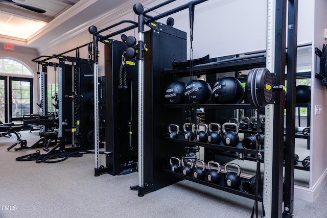 exercise room with a raised ceiling and ornamental molding