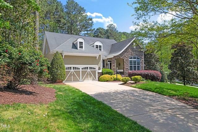 view of front of home featuring driveway, a front yard, stone siding, and a garage
