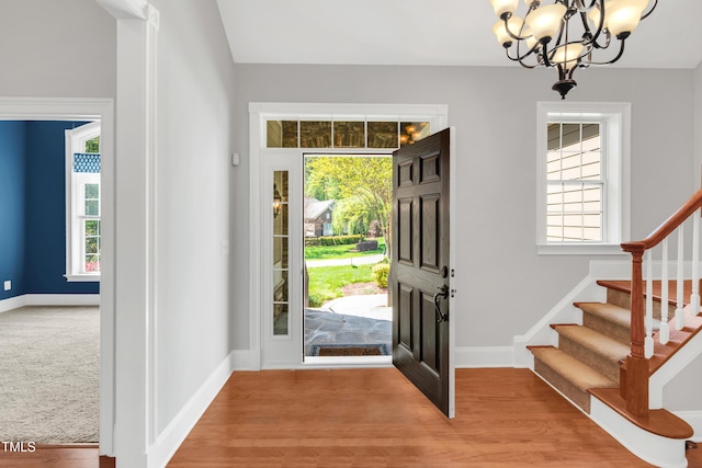 entrance foyer featuring stairs, an inviting chandelier, and a healthy amount of sunlight