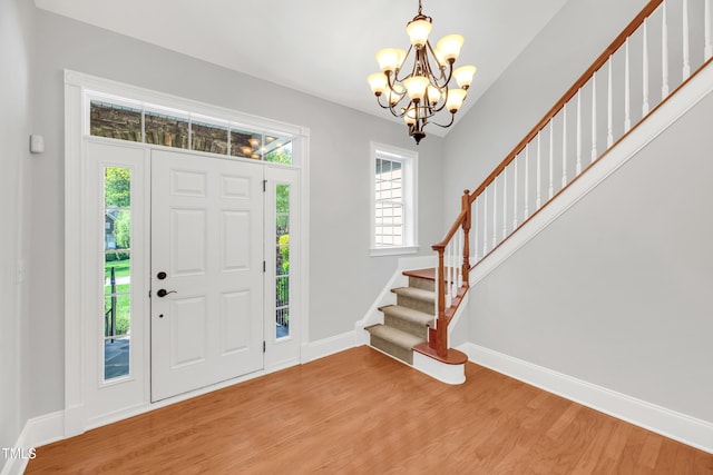 entrance foyer with a chandelier, light wood-style floors, baseboards, and stairway