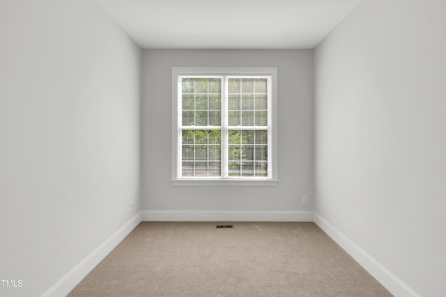 empty room with light colored carpet, baseboards, and a healthy amount of sunlight