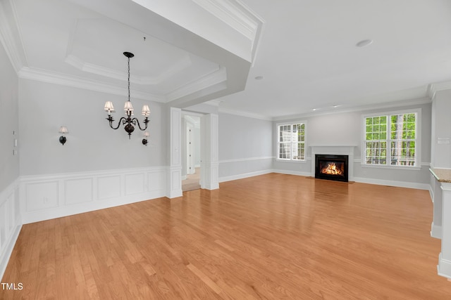 unfurnished living room with crown molding, light wood finished floors, a notable chandelier, and a fireplace with flush hearth