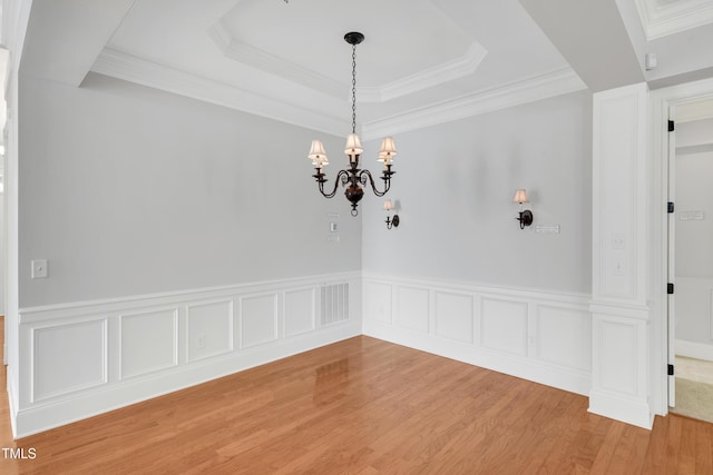 unfurnished dining area featuring wood finished floors, a notable chandelier, visible vents, and a wainscoted wall