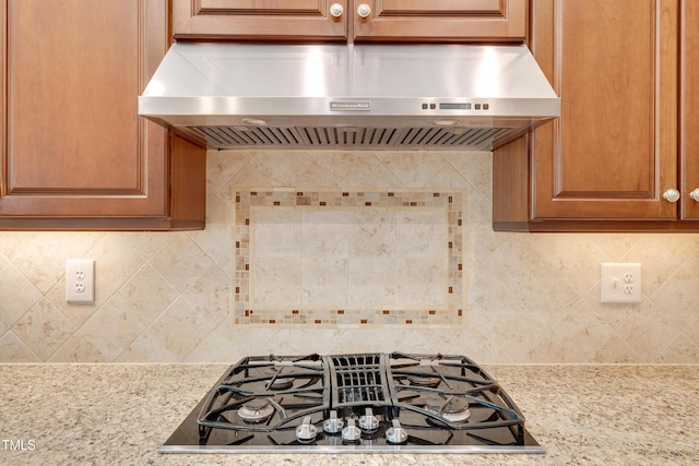 details with tasteful backsplash, under cabinet range hood, stovetop with downdraft, and light stone counters