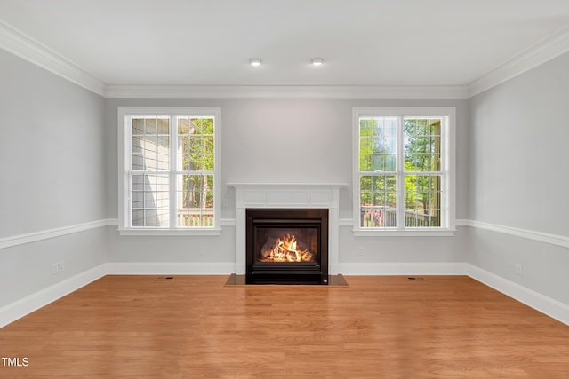 unfurnished living room featuring a fireplace with flush hearth, crown molding, and plenty of natural light