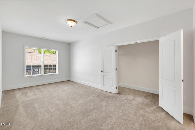 unfurnished bedroom featuring a closet, attic access, baseboards, and carpet floors