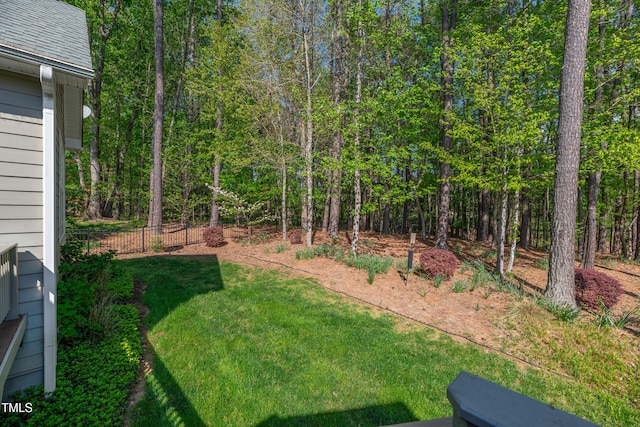 view of yard featuring a forest view and fence