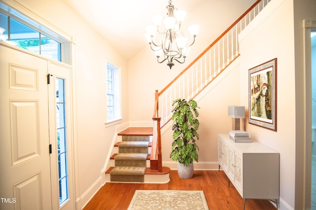 entrance foyer featuring stairs, a notable chandelier, baseboards, and wood finished floors