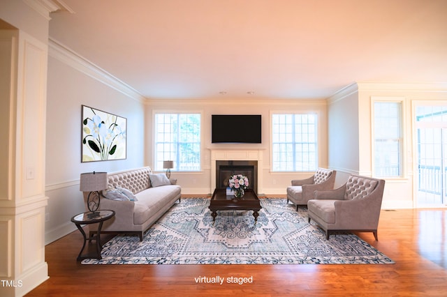 living area featuring a fireplace, baseboards, crown molding, and wood finished floors