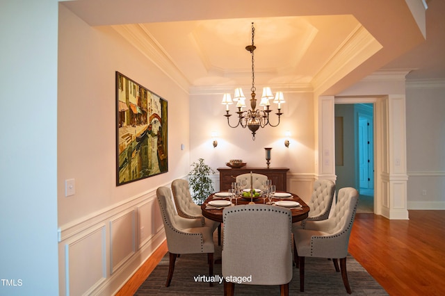dining area featuring a tray ceiling, crown molding, wood finished floors, and a notable chandelier