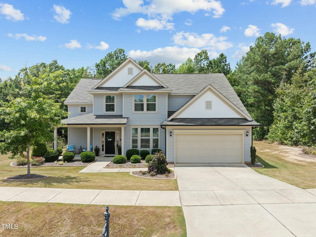 view of front of house with a porch, a garage, and a front lawn