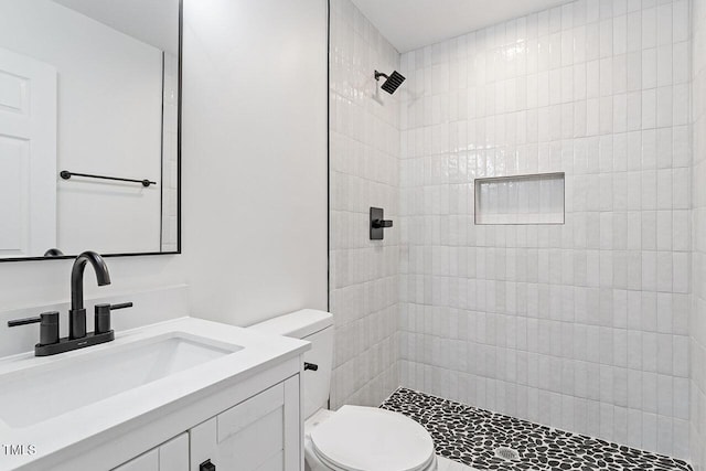 bathroom with vanity, toilet, and tiled shower