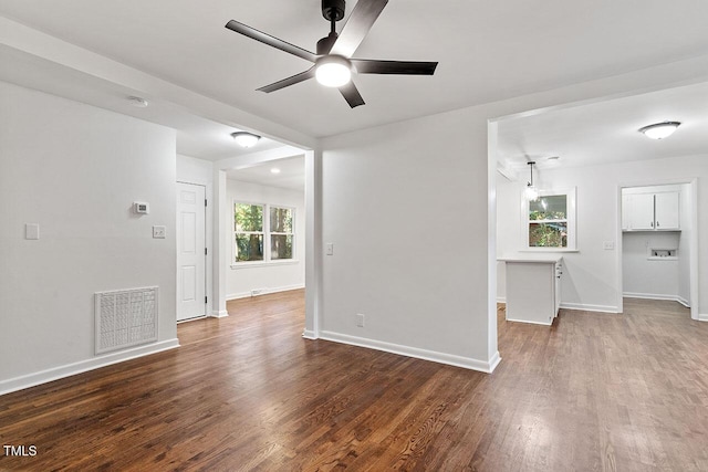 unfurnished room with a wealth of natural light, ceiling fan, and dark wood-type flooring