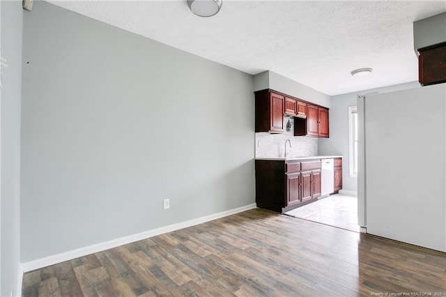 kitchen featuring a textured ceiling, decorative backsplash, wood-type flooring, and white appliances