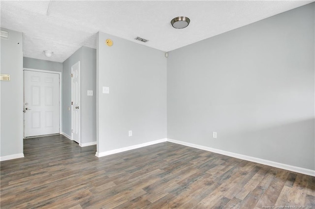 empty room featuring a textured ceiling and dark wood-type flooring