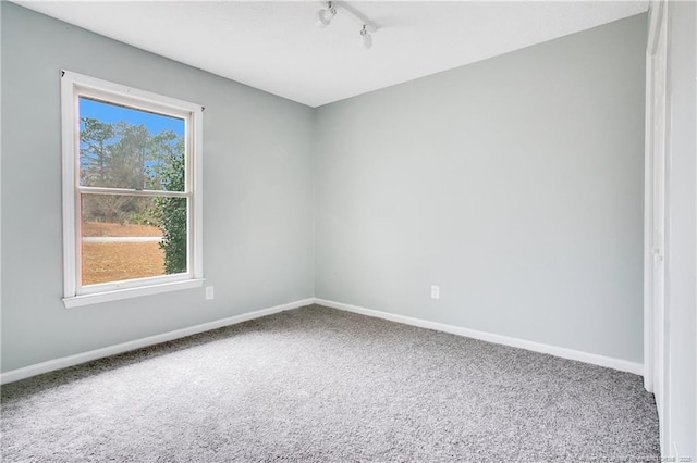 carpeted empty room featuring track lighting