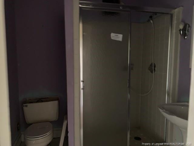 bathroom with a shower with door and toilet