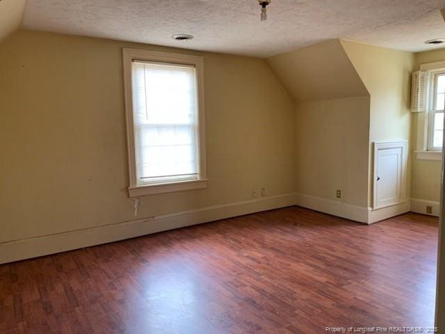 bonus room featuring a textured ceiling, hardwood / wood-style flooring, and lofted ceiling