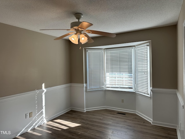 empty room featuring dark hardwood / wood-style floors, ceiling fan, and a textured ceiling