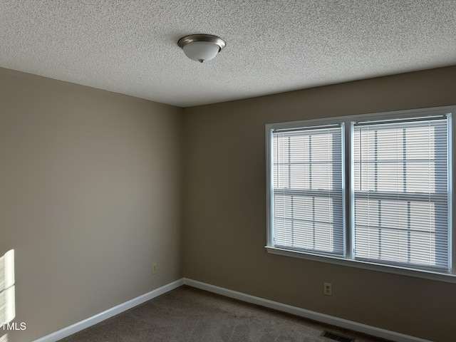 carpeted empty room featuring a textured ceiling