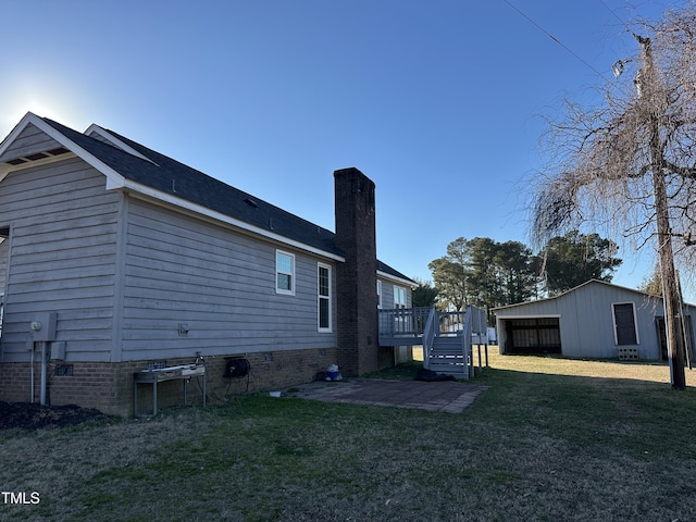 rear view of house with an outbuilding, a deck, and a lawn