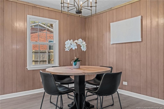 dining room featuring hardwood / wood-style floors, wooden walls, and a chandelier