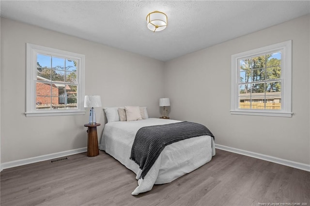 bedroom with light hardwood / wood-style floors and multiple windows