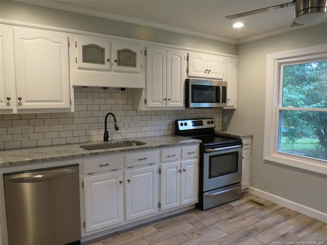 kitchen featuring white cabinetry, sink, stainless steel appliances, light stone counters, and light hardwood / wood-style flooring