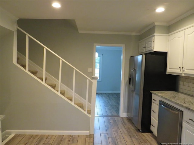 kitchen with white cabinets, decorative backsplash, crown molding, and stainless steel appliances