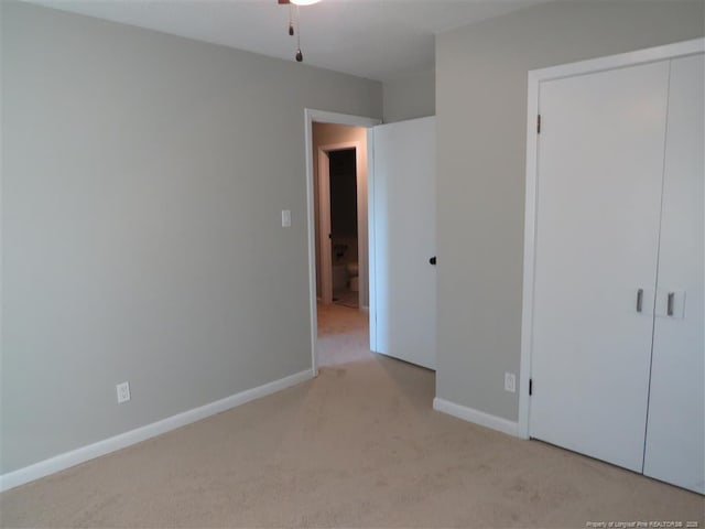 unfurnished bedroom featuring light carpet and a closet