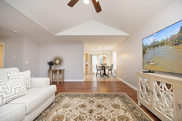 living room with ceiling fan with notable chandelier, hardwood / wood-style floors, and vaulted ceiling